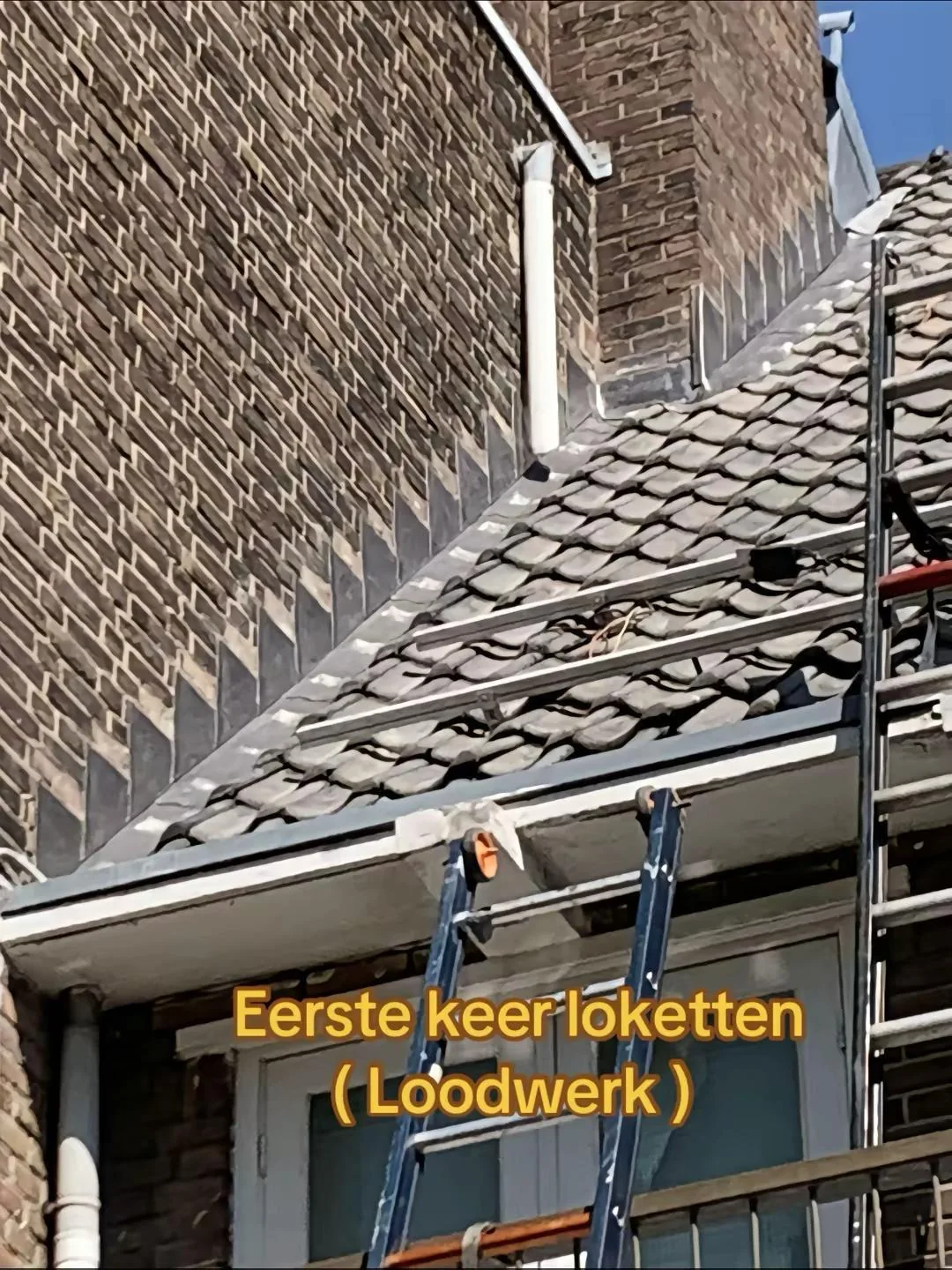 Loodloketten langs de overgang van een pannendak naar een gemetselde gevel.
