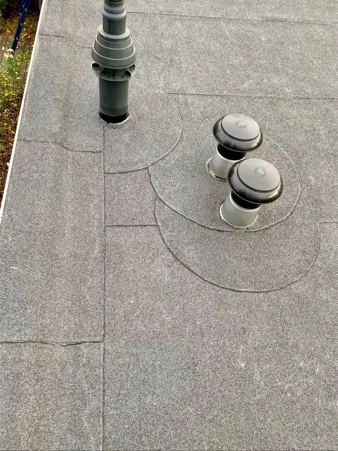 Drie doorvoeren met aansluitstroken in de platte dakbedekking.