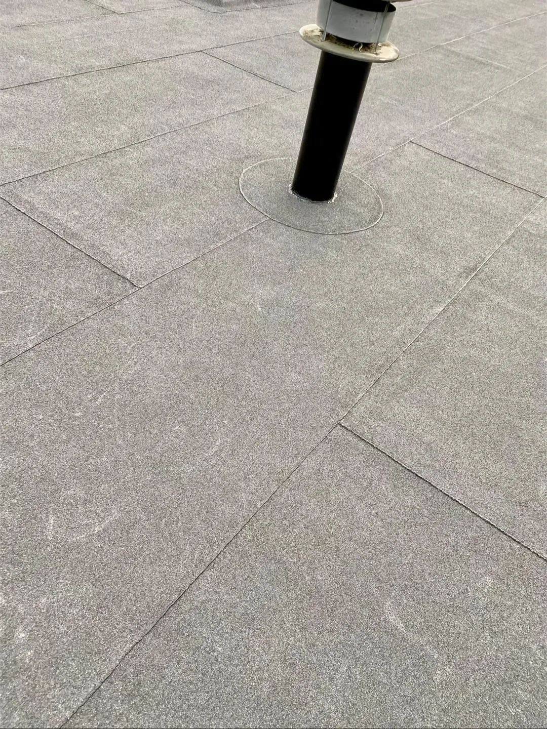 Ronde pijp met een aansluiting in de banen dakbedekking.