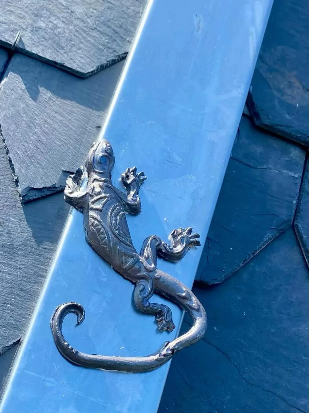 Sierfiguur op een metalen dakdetail naast de leien.