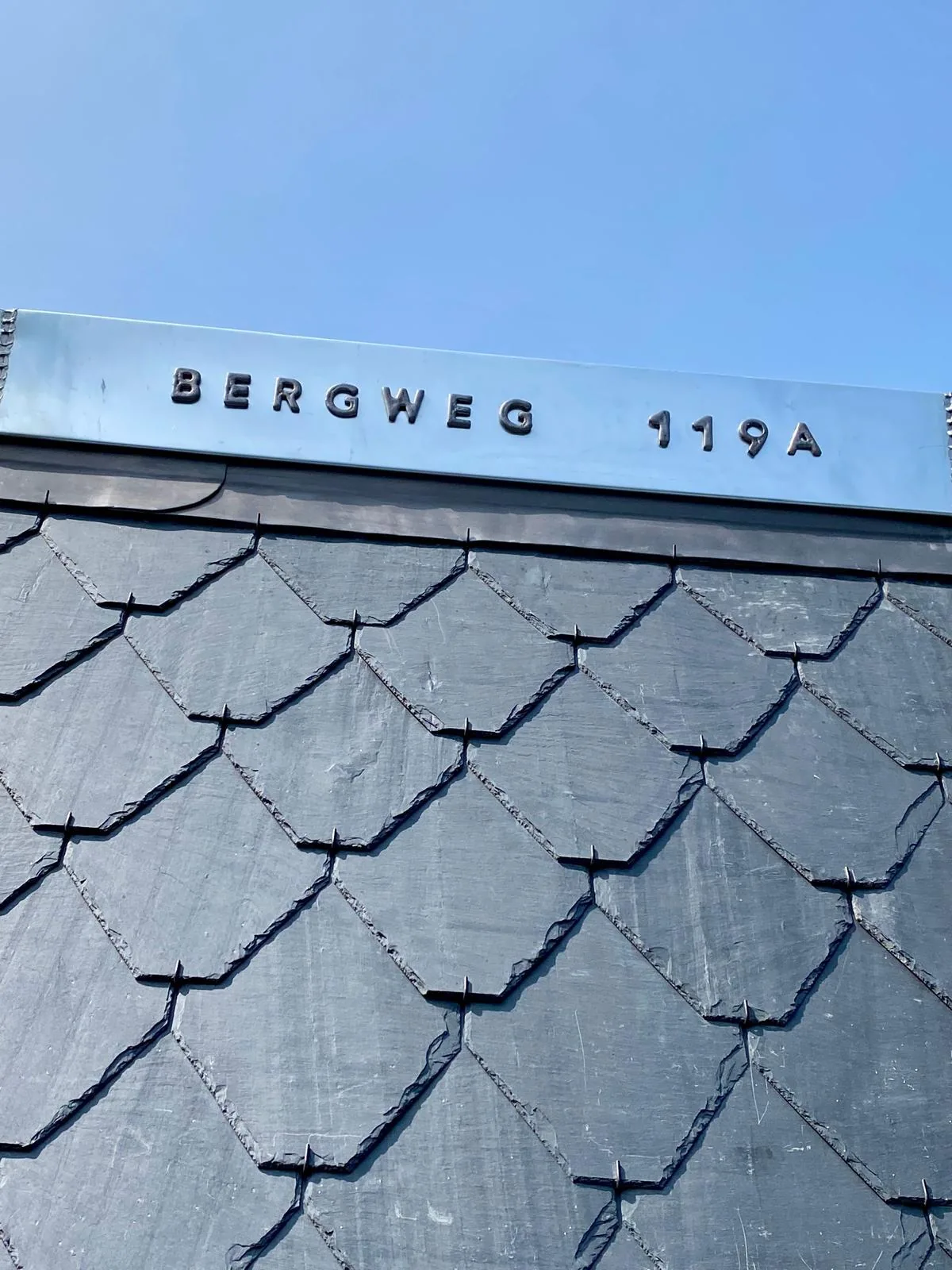 Zinken randafwerking met een uitgesneden letterdetail boven leien.